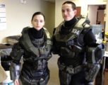 Behind the scenes photo of the actress of Kelly-087 standing next to the actor of Frederic-104 in armor.